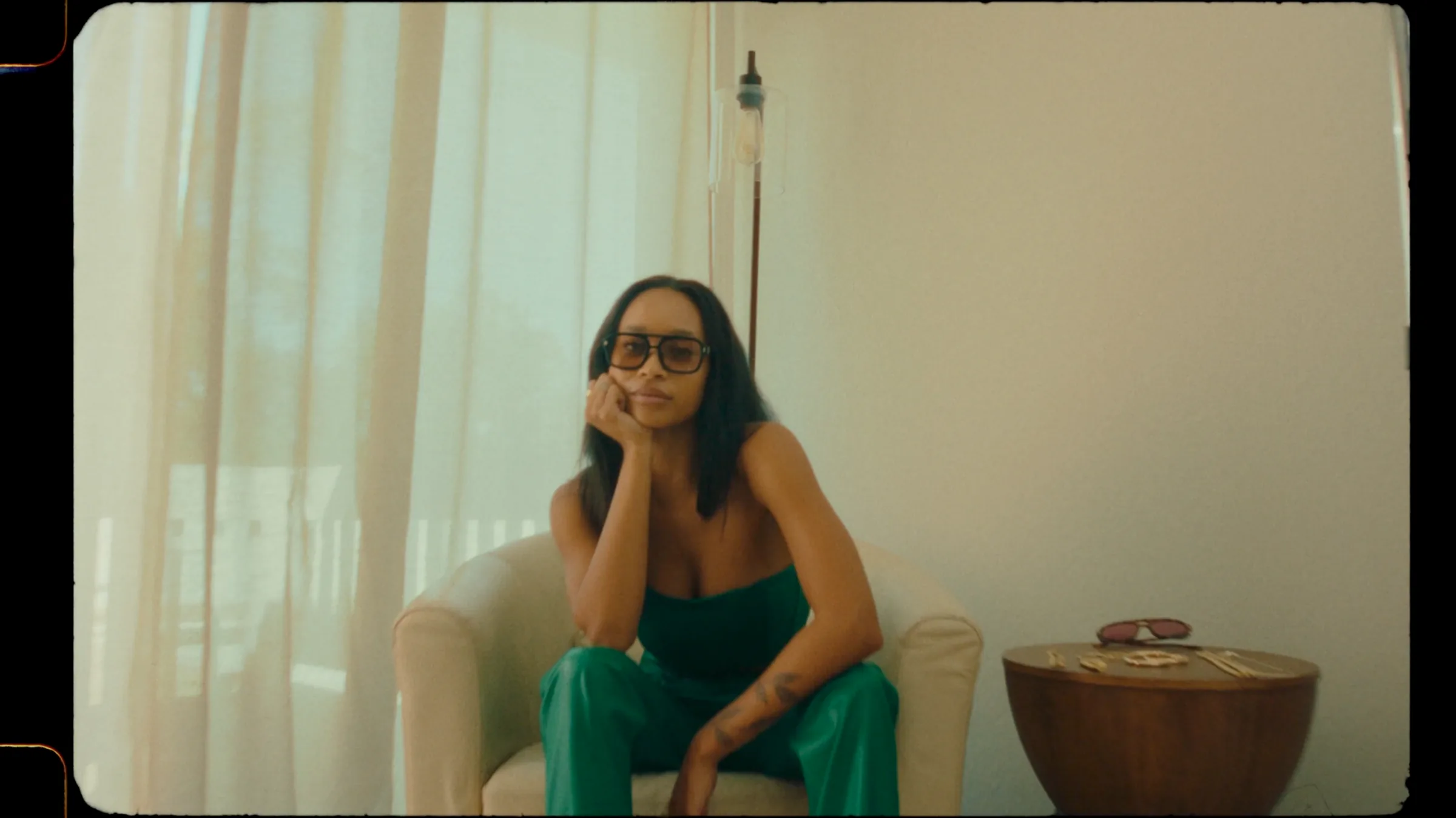 Model in a green look seated in a cream chair